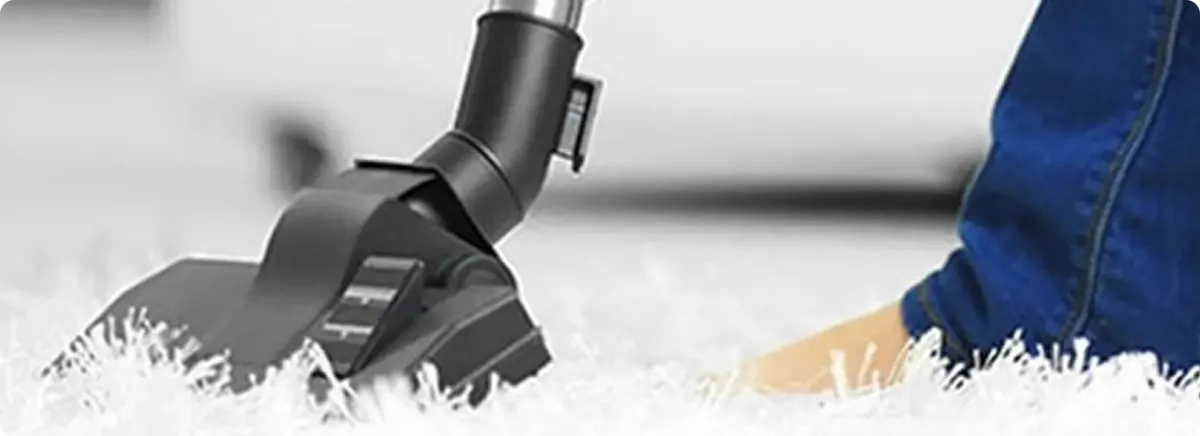 Close-up of a professional vacuuming a white carpet in Hooksett.